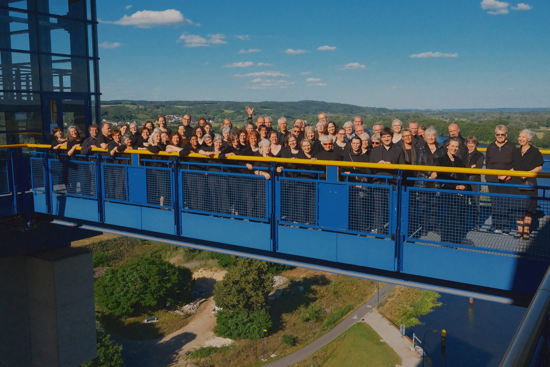 Ein großer Chor singt auf der blauen Brücke des Hebewerks, darunter Wald und Wiesen