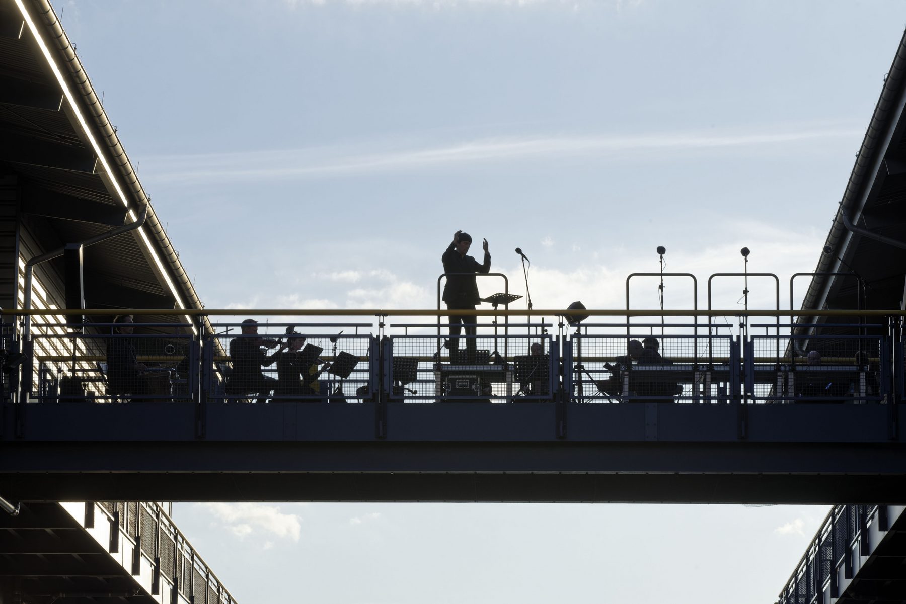 Ein Dirigent in Silhouette auf der Brücke des Hebewerks vor hellem Himmel
