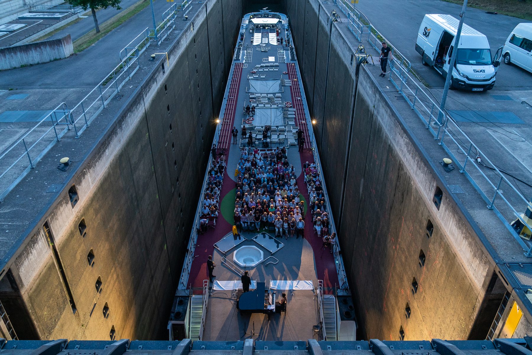 Blick von oben in die Schleusenkammer: das Schiff mit dem Publikum an Deck, rechts und links die hohen Kammerwände